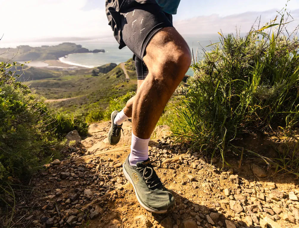 Man running on the hills with beach in the background