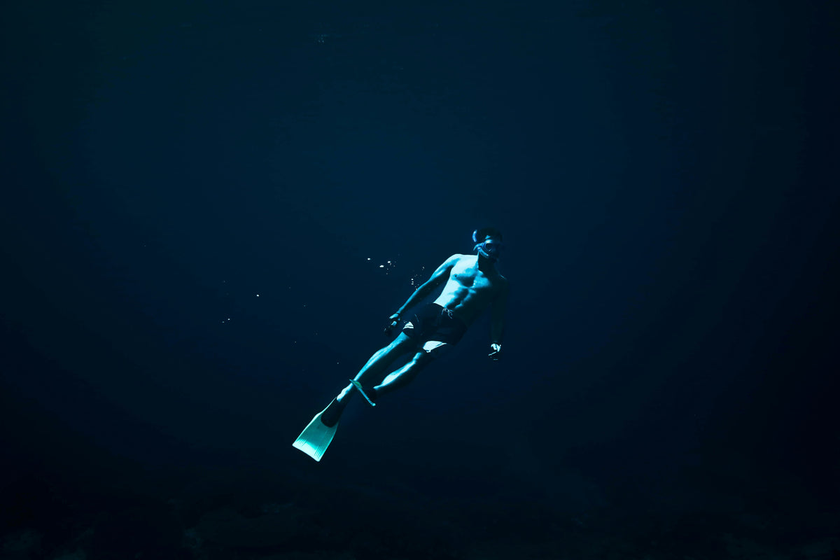 A man diving in dark deep waters