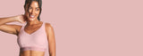 Smiling Woman posing with a Bra in a pink background